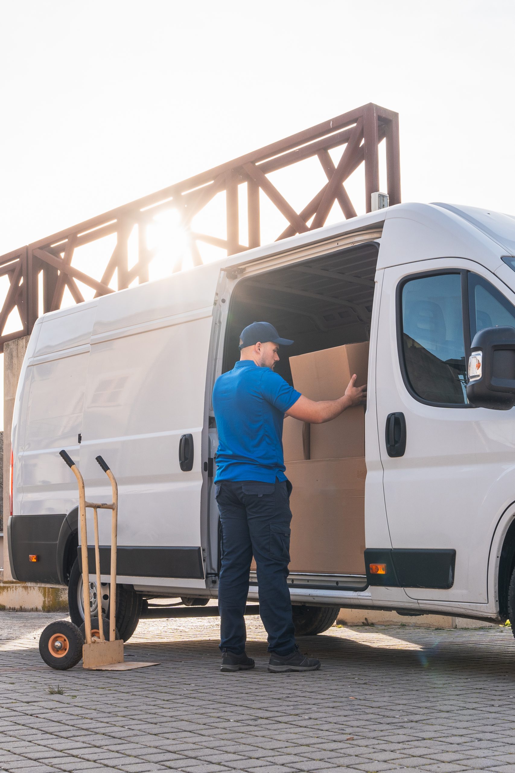 Delivery man loading cardboard boxes into white van